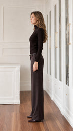 Side profile view of model wearing black high neck knit top