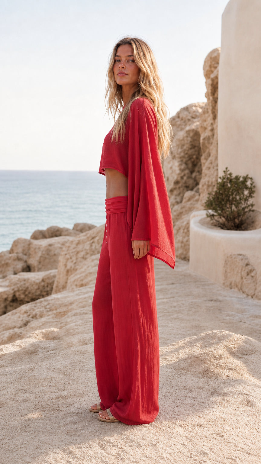Side profile of women wearing red wide leg pants and batwing crop top set