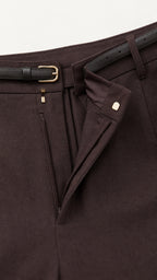 Detail view of dark tailored trousers waistband and belt closure
