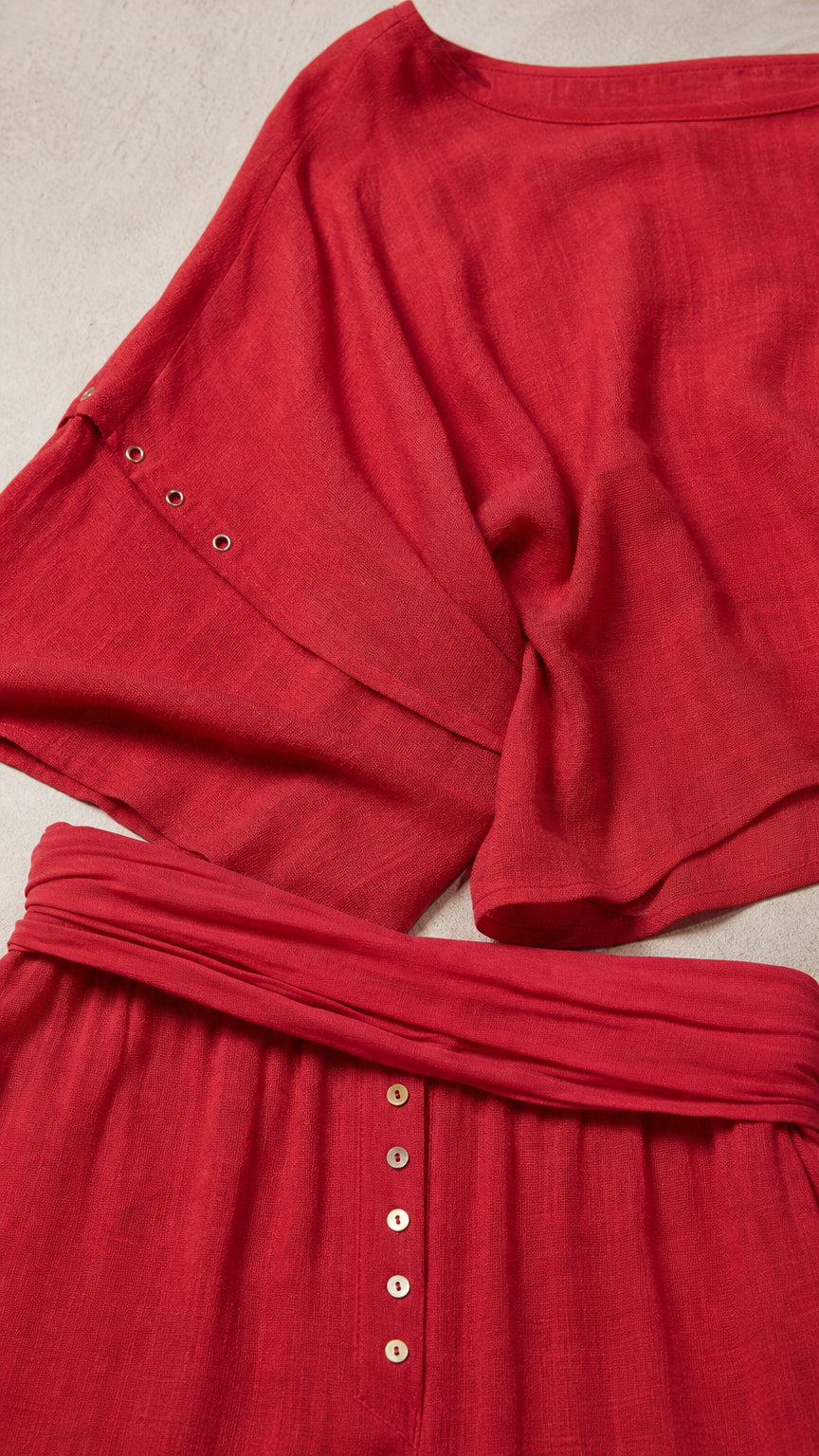 Close-up detail of red textured fabric and button embellishments on waist and sleeve
